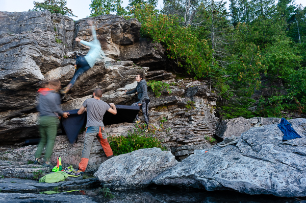 four people bouldering on the shore of lake huron