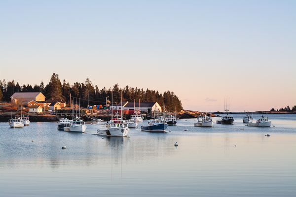 a picture of the sun set over a harbor full of lobster boats
