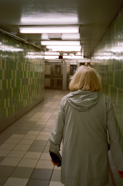 a photography of a woman walking in a subway tunnel